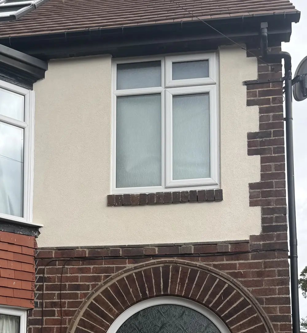 The same Sheffield elevation after repair, the panel taken back and re-rendered flat with the brick quoins and door arch left exposed